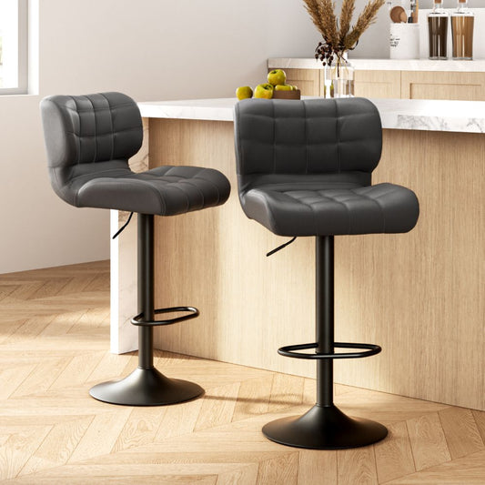 Two black bar stools with quilted seats in a kitchen setting.