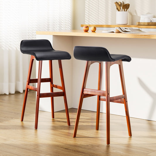 Two black bar stools with wooden legs in a kitchen setting.
