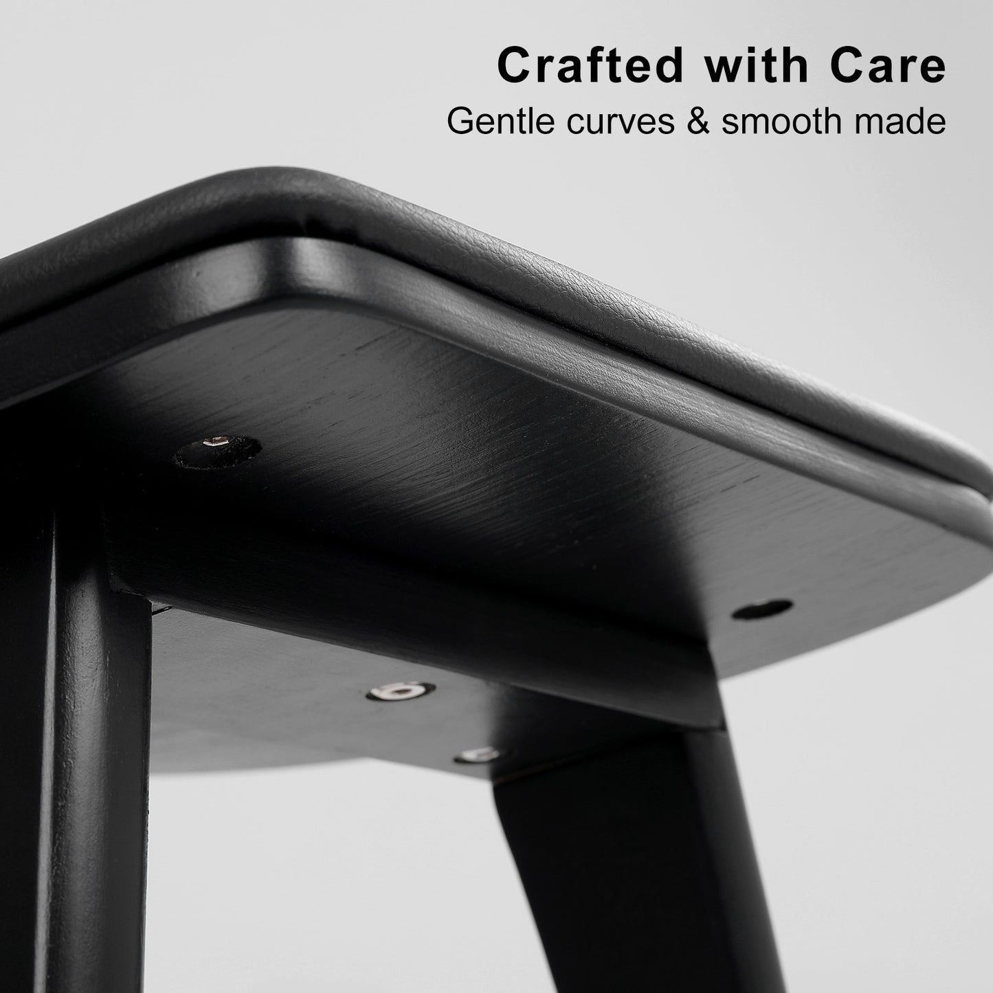 Close-up of a black metal stool with 'Crafted with Care' text on a gray background