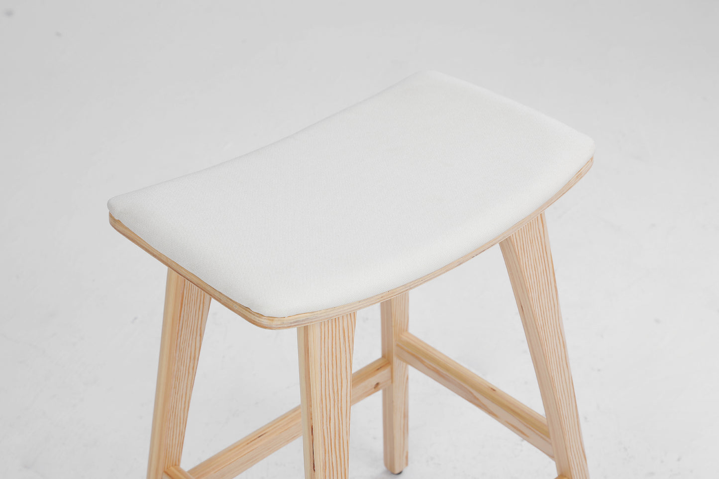 Stool with white cushioned seat and wooden legs on a light gray background