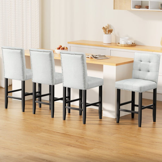Four grey cushioned bar stools with black legs around a wooden dining table in a kitchen.