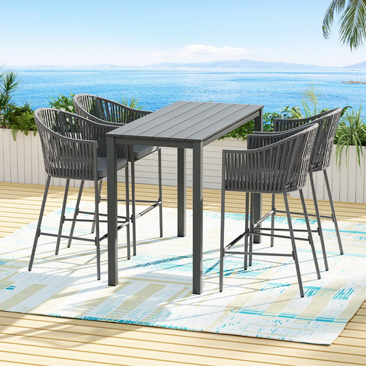 Outdoor dining set with high chairs on a deck overlooking the ocean.