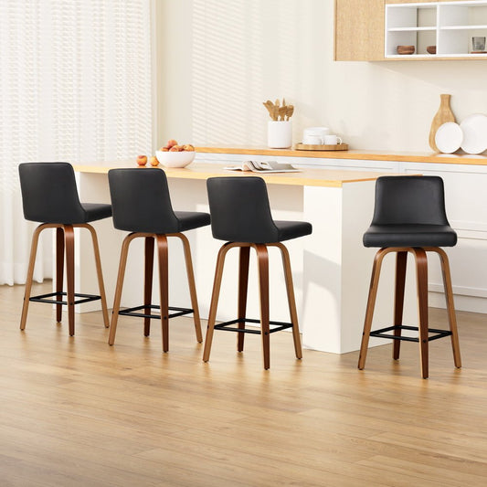 Four black bar stools with wooden legs in a kitchen setting.