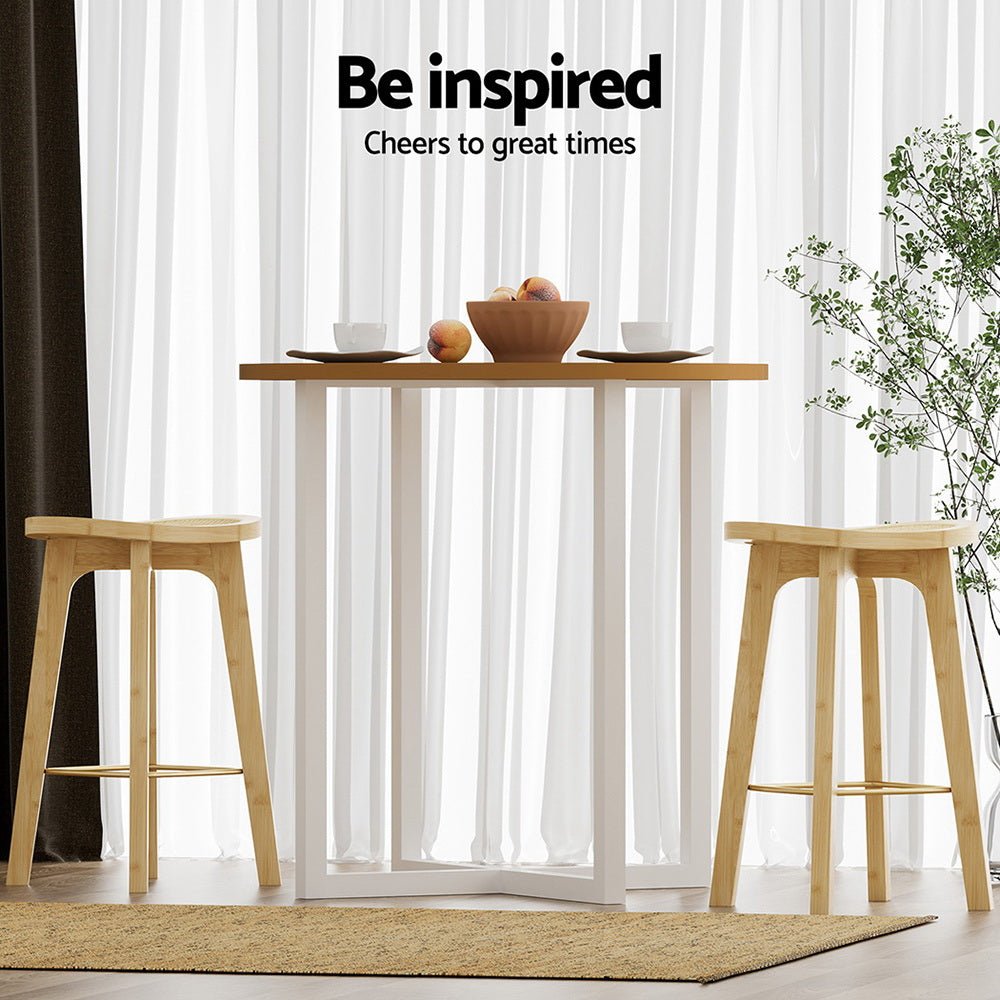 Wooden table with two stools in a room with white curtains and a plant.