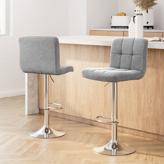 Two grey upholstered bar stools with metal bases in a kitchen setting
