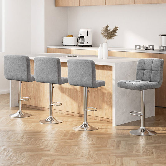 Four grey bar stools in a modern kitchen setting with wooden flooring and white walls