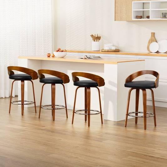 Four wooden bar stools with black seats in a kitchen setting.