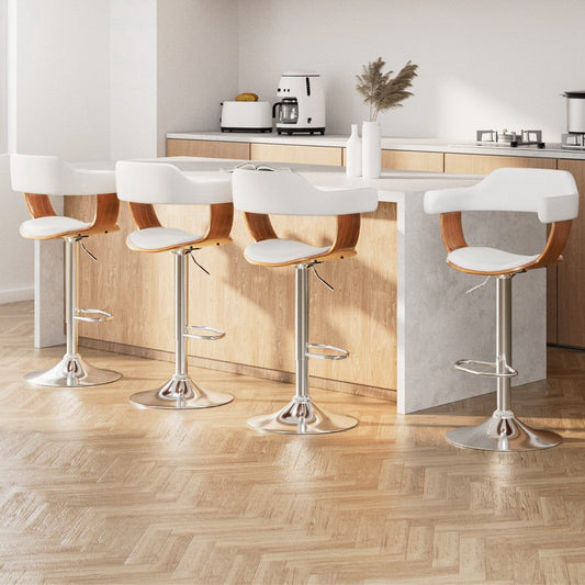 Four modern bar stools with white seats and wooden backs around a kitchen island.