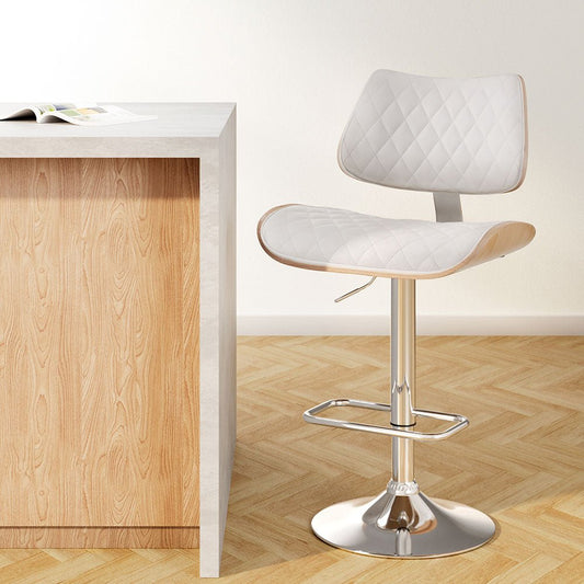 White quilted bar stool next to a wooden counter on a wooden floor.