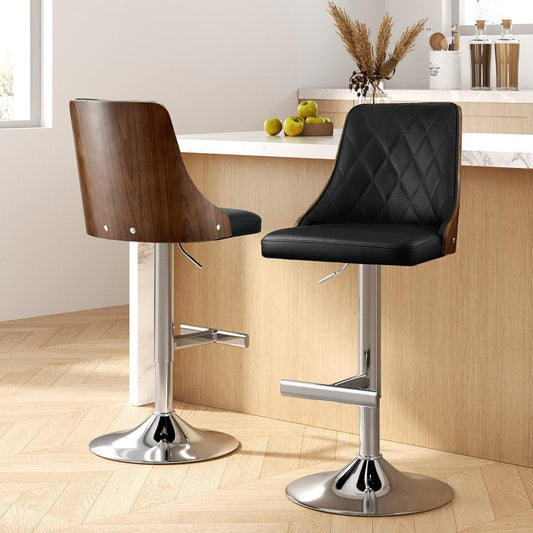 Two bar stools, with wooden backrest and black diamond patterned leather seat, in a kitchen setting.