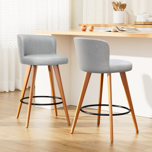 Two grey cushioned bar stools with wooden legs in a kitchen setting