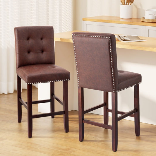Two brown bar stools with tufted seats and nailhead trim in a kitchen setting.
