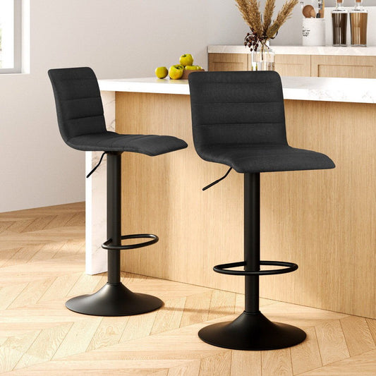 Two black bar stools in a kitchen setting with a wooden counter