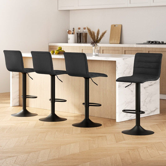 Four black bar stools in a modern kitchen setting with marble island and wooden floor