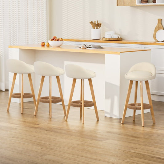 Four bar stools with wooden legs and white seats in a kitchen setting.