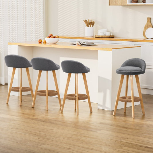 Four bar stools with gray seats and wooden legs in a kitchen setting.