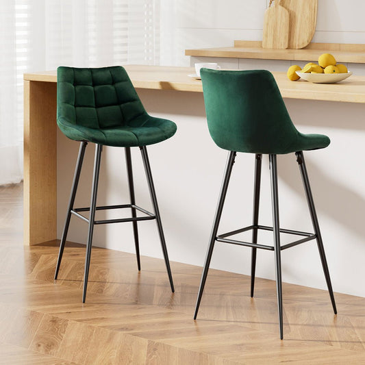 Two green velvet bar stools with black legs in a kitchen setting