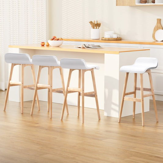 Four white bar stools with wooden legs in front of a kitchen counter.