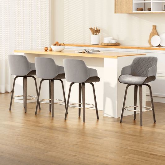Grey fabric bar stools with dark timber legs in a kitchen setting with a wooden floor and countertop.