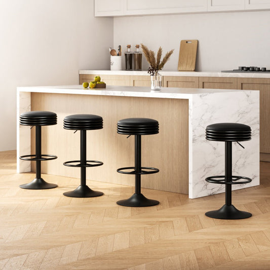 Four black bar stools in a modern kitchen setting with a marble island.
