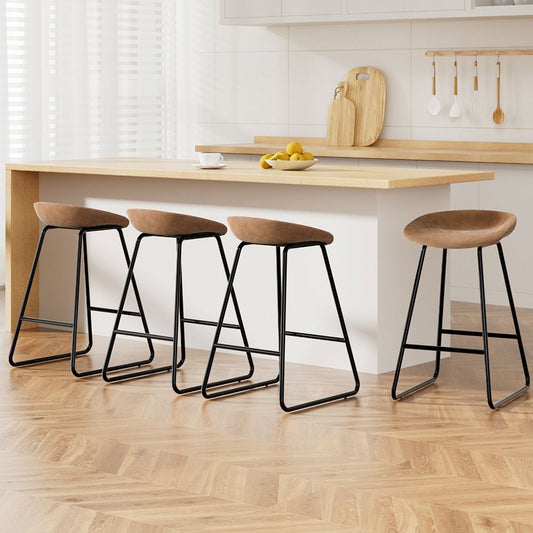Four bar stools with wooden seats and black metal legs in a kitchen setting.