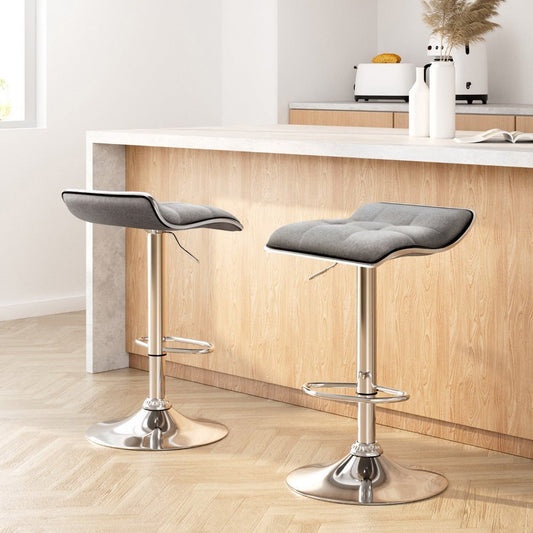 Two grey cushioned bar stools with chrome bases in a kitchen setting