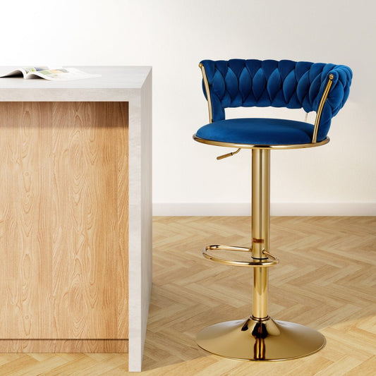 Blue velvet bar stool with gold base next to a wooden counter on a light wood floor