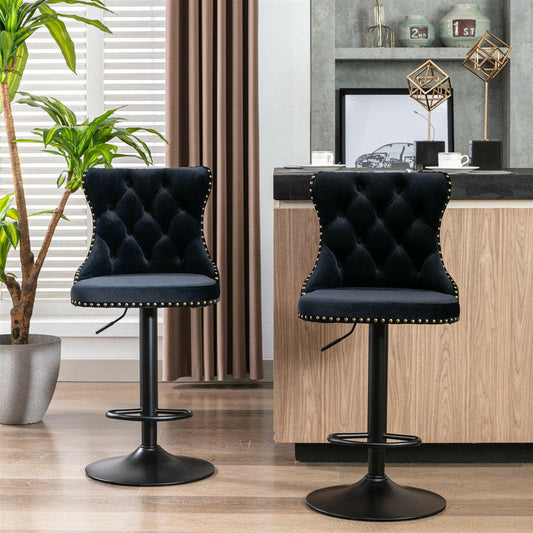 Two black tufted bar stools in a modern kitchen setting with a potted plant and kitchen counter