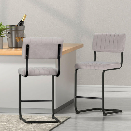 Two grey bar stools with black frames in a room with a table and decor items
