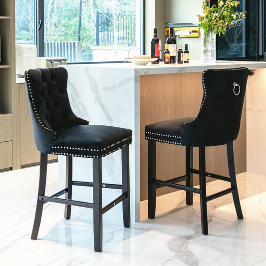 Two black bar stools with nailhead trim in a modern kitchen setting