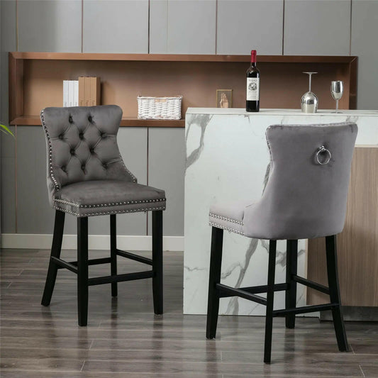 Two grey velvet bar stools with black legs in front of a marble counter