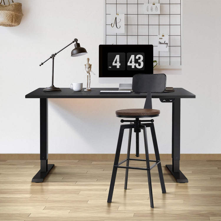 Black adjustable desk with industrial bar stool in a home office setting