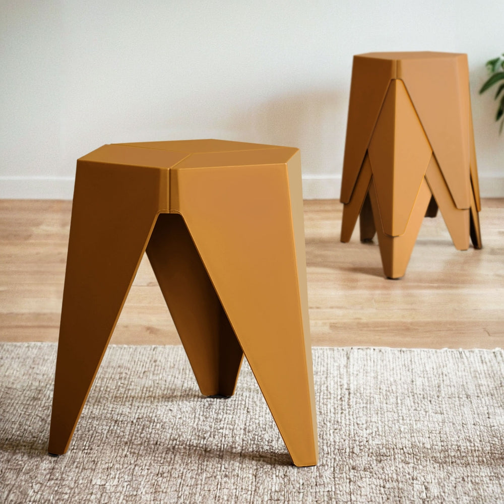 Two mustard yellow geometric stools on a wooden floor with a white wall in the background.