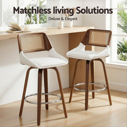 Two bar stools with wooden frames and white seats in a room with a table and plants.