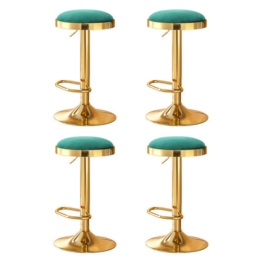 Four gold bar stools with green seats on a white background