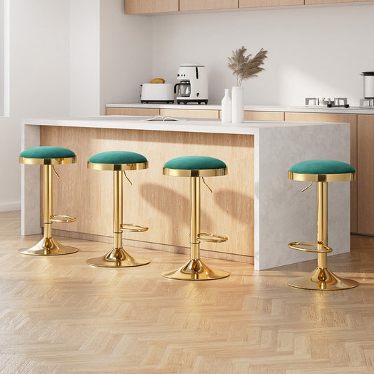 Four green bar stools with gold bases in a modern kitchen setting.