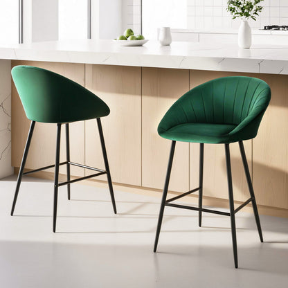 Two green bar stools with black legs in a kitchen setting.