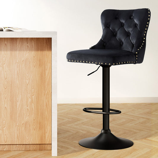 Black tufted bar stool with nailhead trim next to a wooden counter.