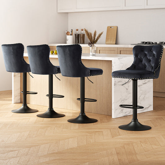 Four black bar stools with tufted seats in a kitchen setting.