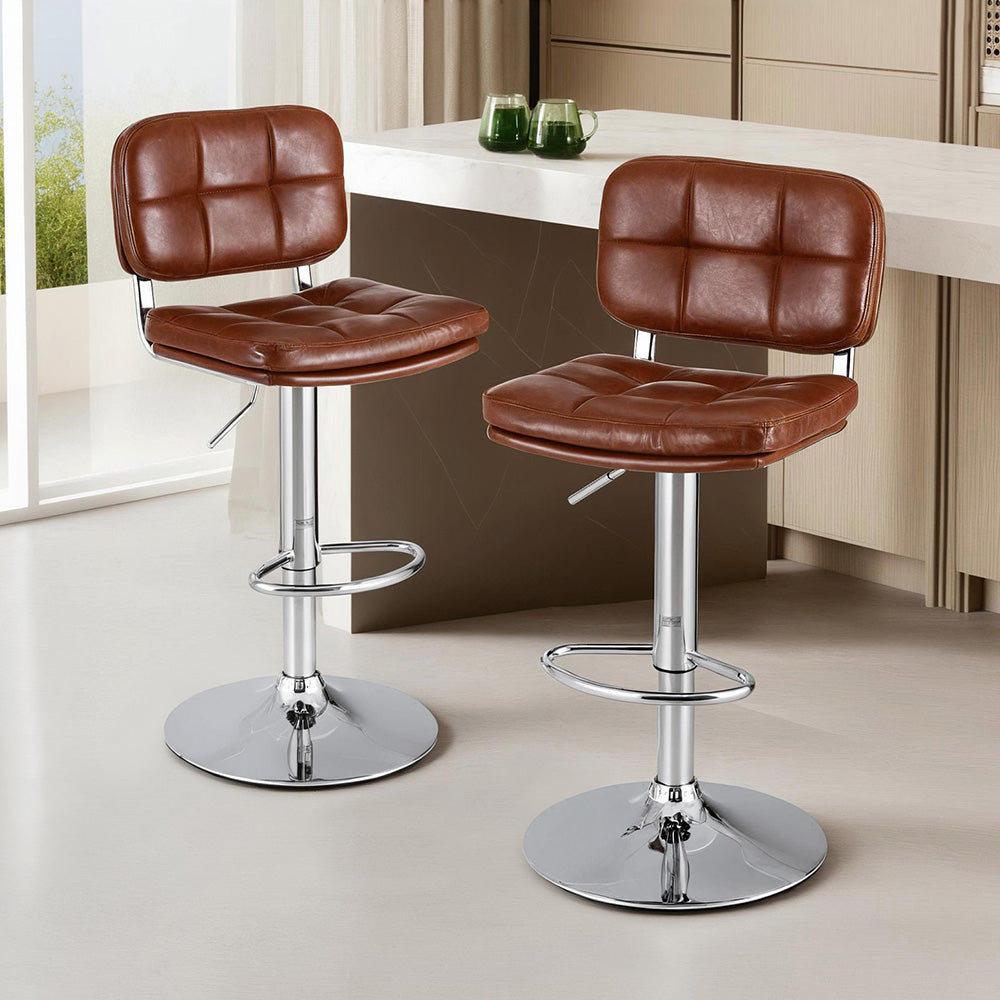Two brown leather bar stools with chrome bases in a kitchen setting.