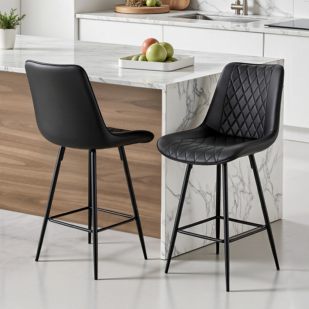 Two black bar stools in front of a kitchen island with marble countertop.