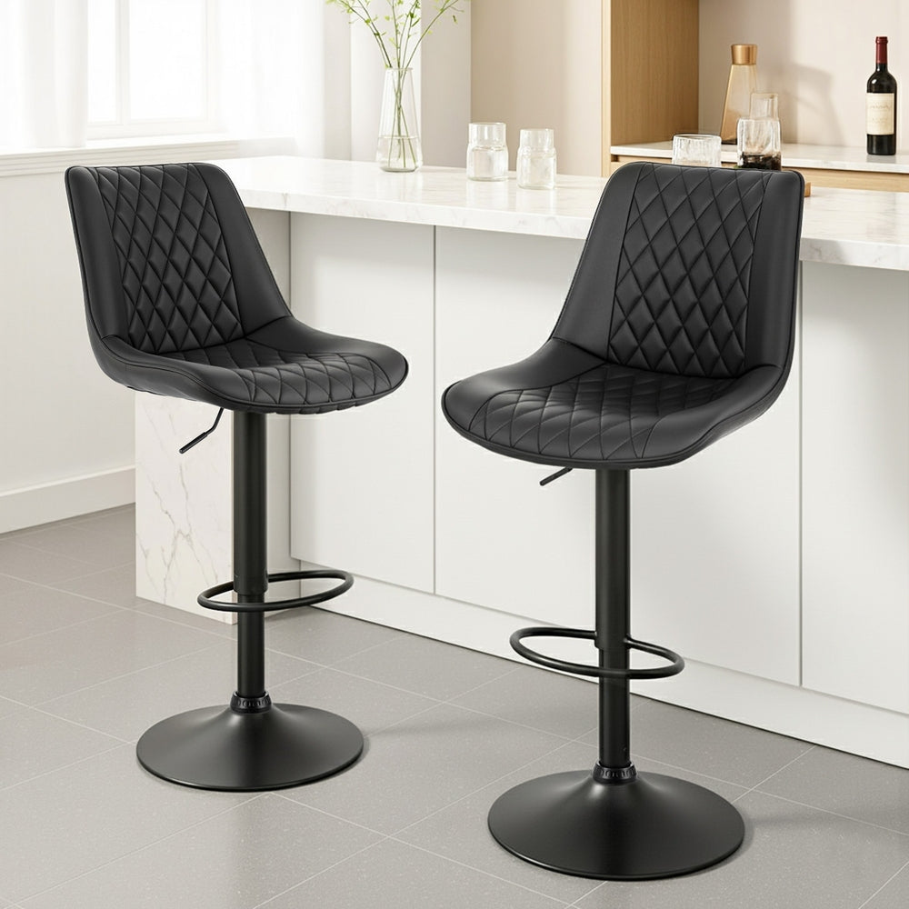 Two black quilted bar stools in a kitchen setting.
