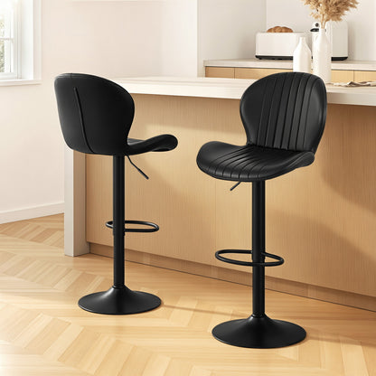 Two black bar stools in a kitchen setting with wooden flooring and white countertops.