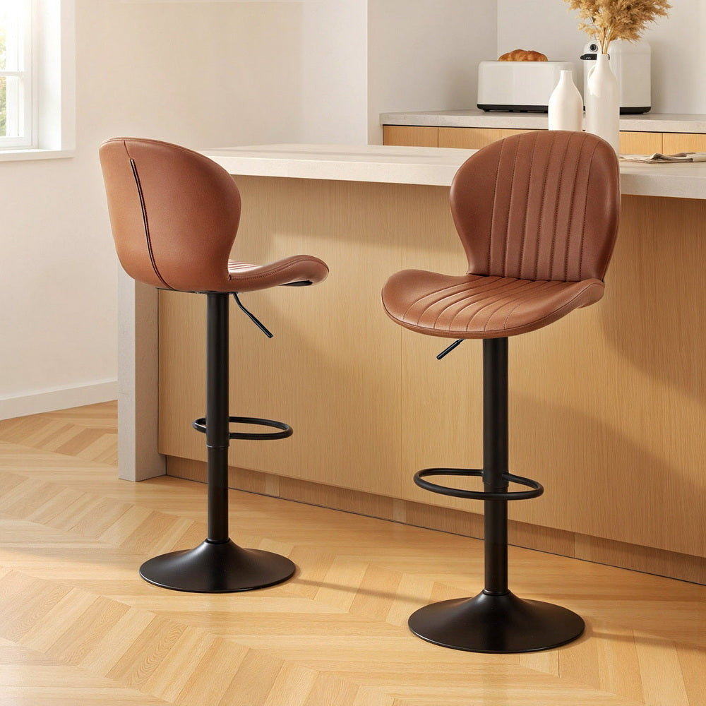 Two brown bar stools with black bases in a kitchen setting.