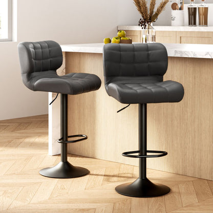 Two black bar stools with quilted seats in a kitchen setting.