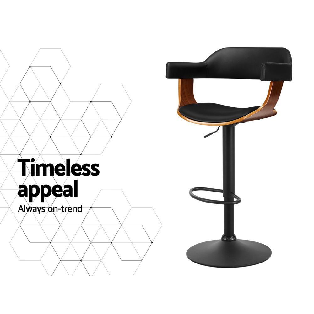 A modern bar stool with a black upholstered seat and curved backrest, supported by a black metal pedestal base with a circular footrest and armrests featuring warm wood-toned sides. The stool is shown on a white background with a geometric line pattern and the text 'Timeless appeal Always on-trend' on the left.