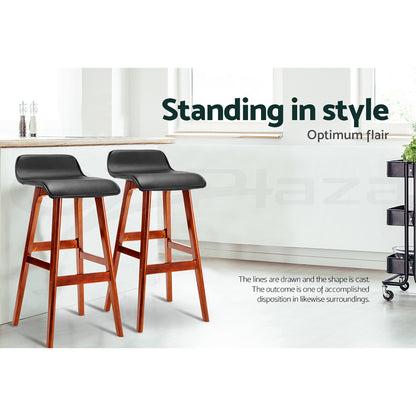 Two bar stools with wooden legs and black seats in a modern kitchen setting.