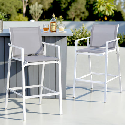 Outdoor setting with two gray high chairs and a small table on a patio.