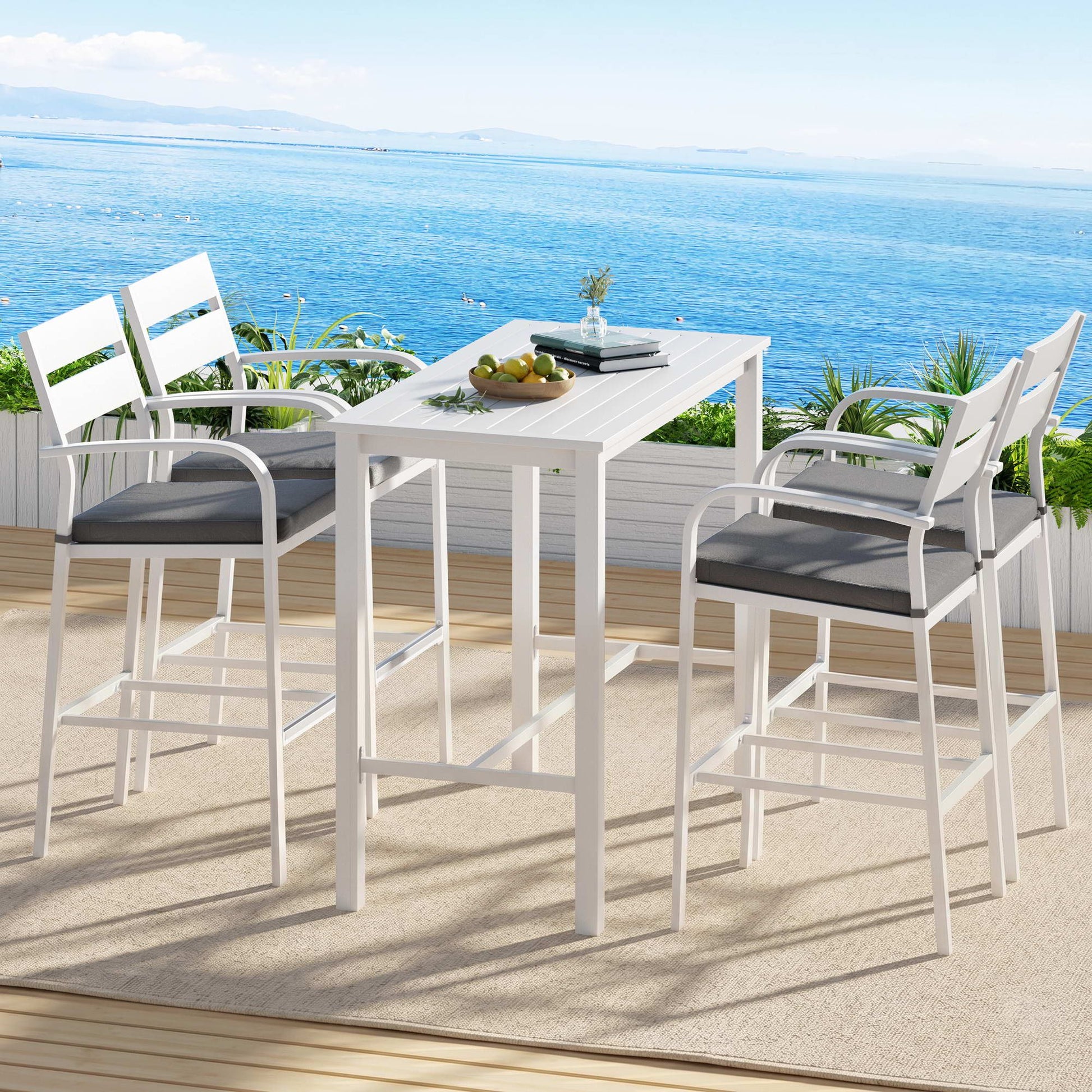 Outdoor dining set with high chairs and table on a deck overlooking the ocean.
