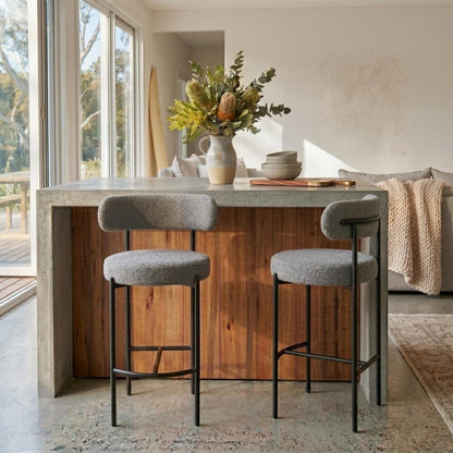 Modern kitchen island with stools and decorative elements in a bright room.